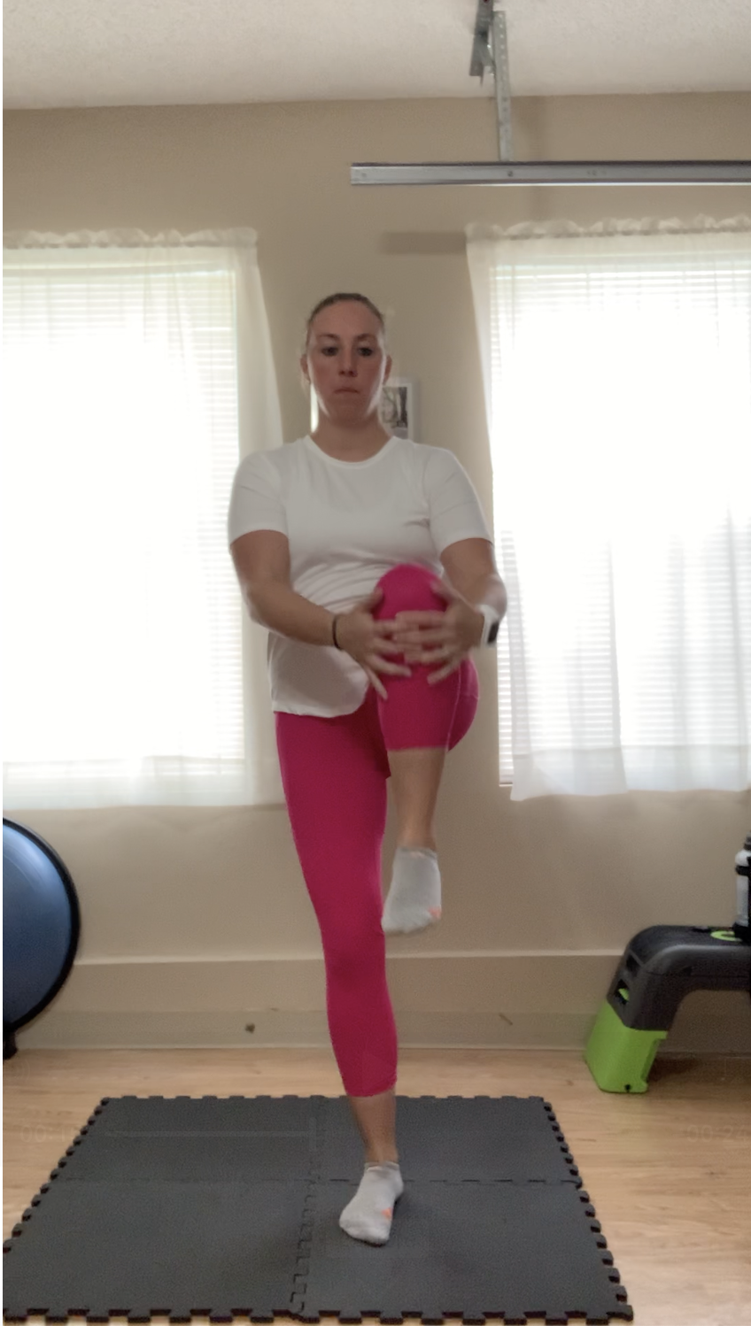 A female standing and grabbing one knee at chest hieight